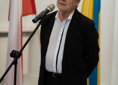 Fotografia. Wernisaż wystawy piękno jedności. jan piekło, były ambasador polski na ukrainie przemawia do mikrofonu. za nim stoją flagi polska i ukraińska.